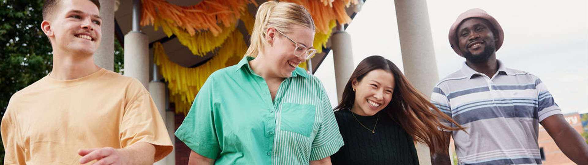 Four students walking outdoors at the Curtin Perth campus laughing. 