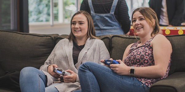 Two women playing playstation sitting on a couch