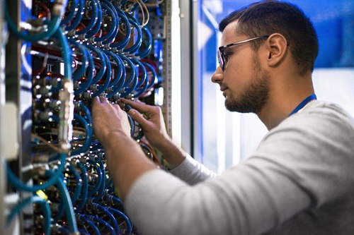 Photo: a person connecting cables in a server cabinet