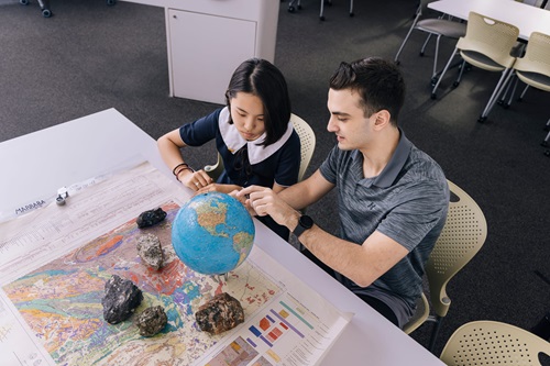 Photo: a student looking at a globe with a school pupil