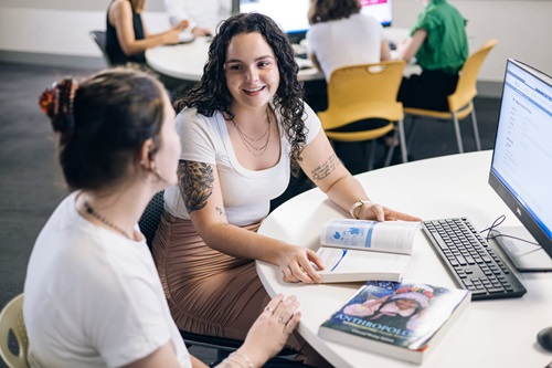 Photo: two Bachelor of Arts students browsing an Anthropology text book