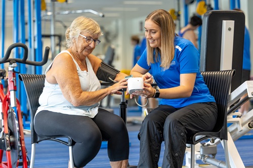 Photo: a student discussing treatment with an elderly patient in a gym setting / Images by Roslyn Budd – Budd Photography