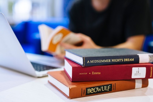 Photo: a student working on their laptop with three English Literature books on the table