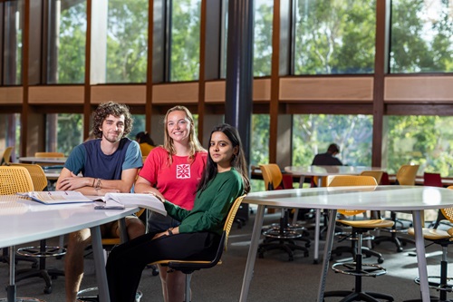 PhotoPhoto: three students sitting in the EIP building looking at text books: three students sitting outside reading text books